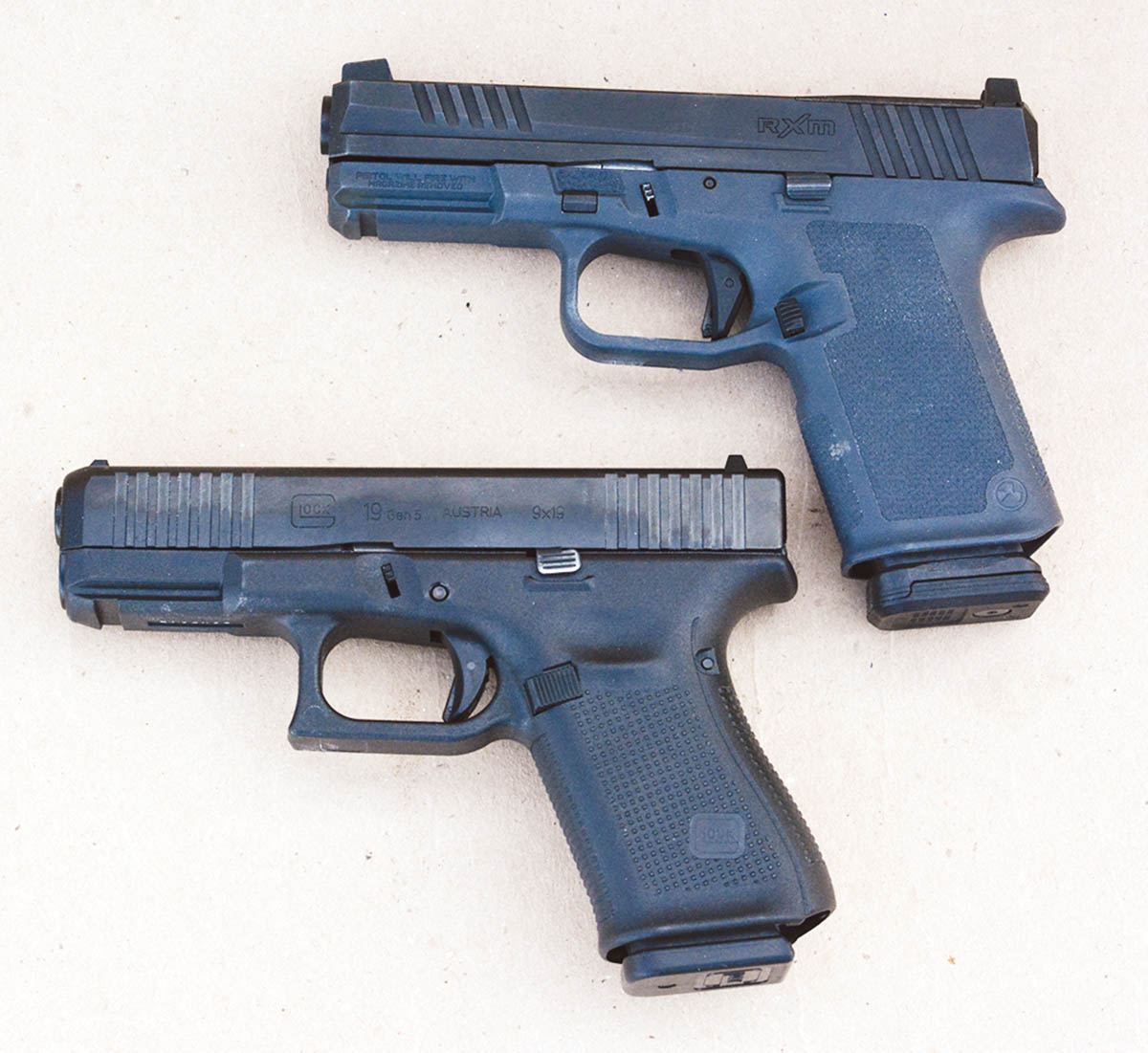 The Ruger RXM (top) is patterned after the Glock 19 (bottom) and accepts Glock Gen 3 accessories.